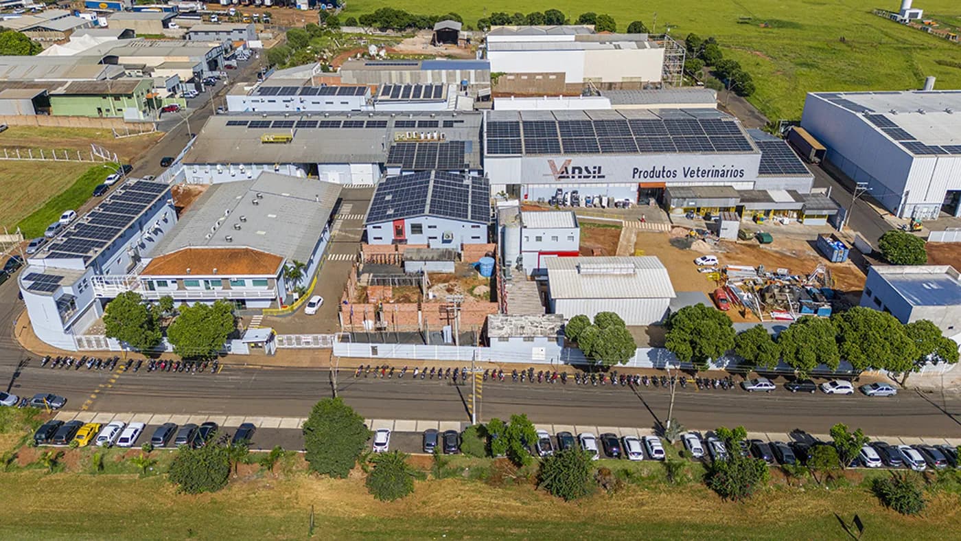 Indústria de saúde animal — vista aérea do complexo industrial com geração fotovoltaica no telhado